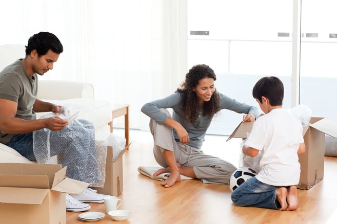 Happy family packing dishes together in their living-room for their removal