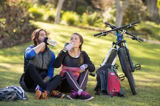 Biker couple relaxing and having water in countryside park.jpeg