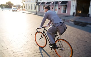 Businessman riding bicycle to work on urban street in morning.jpeg