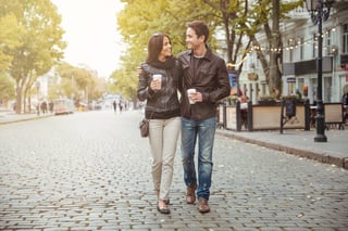 Portrait of a happy romantic couple with coffee walking outdoors in old european city.jpeg