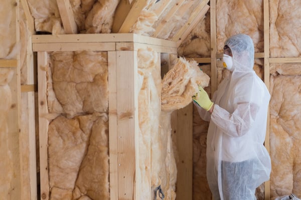 Worker filling walls with insulation material in construction site